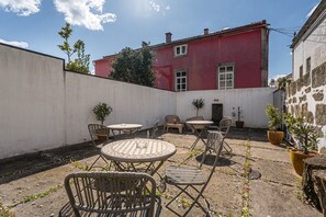 Une cour avec un bâtiment rouge, des sièges en plein air et des plantes en pot.