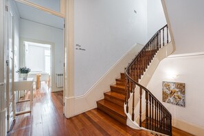 Uma escada com degraus de madeira e corrimão de metal, conduzindo a um andar superior.