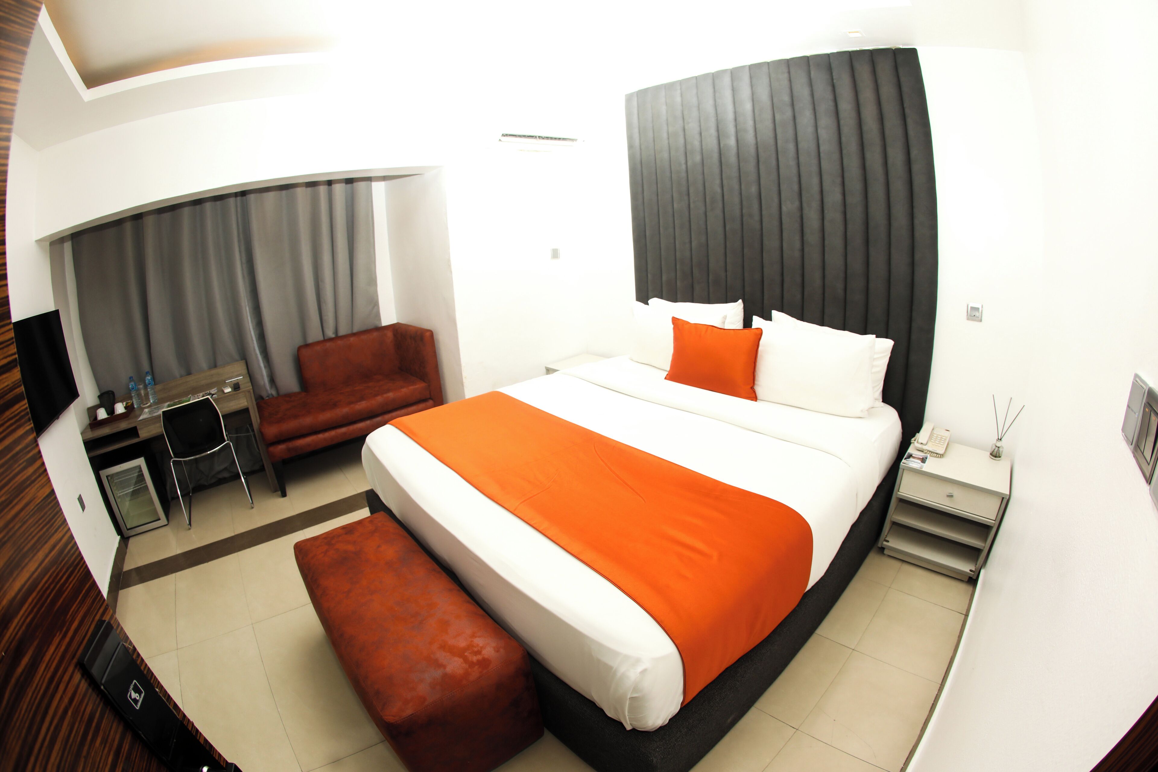 Ein modernes Hotelzimmer mit einem großen Bett, einem Schreibtisch, einem Stuhl und einem kleinen Tisch.