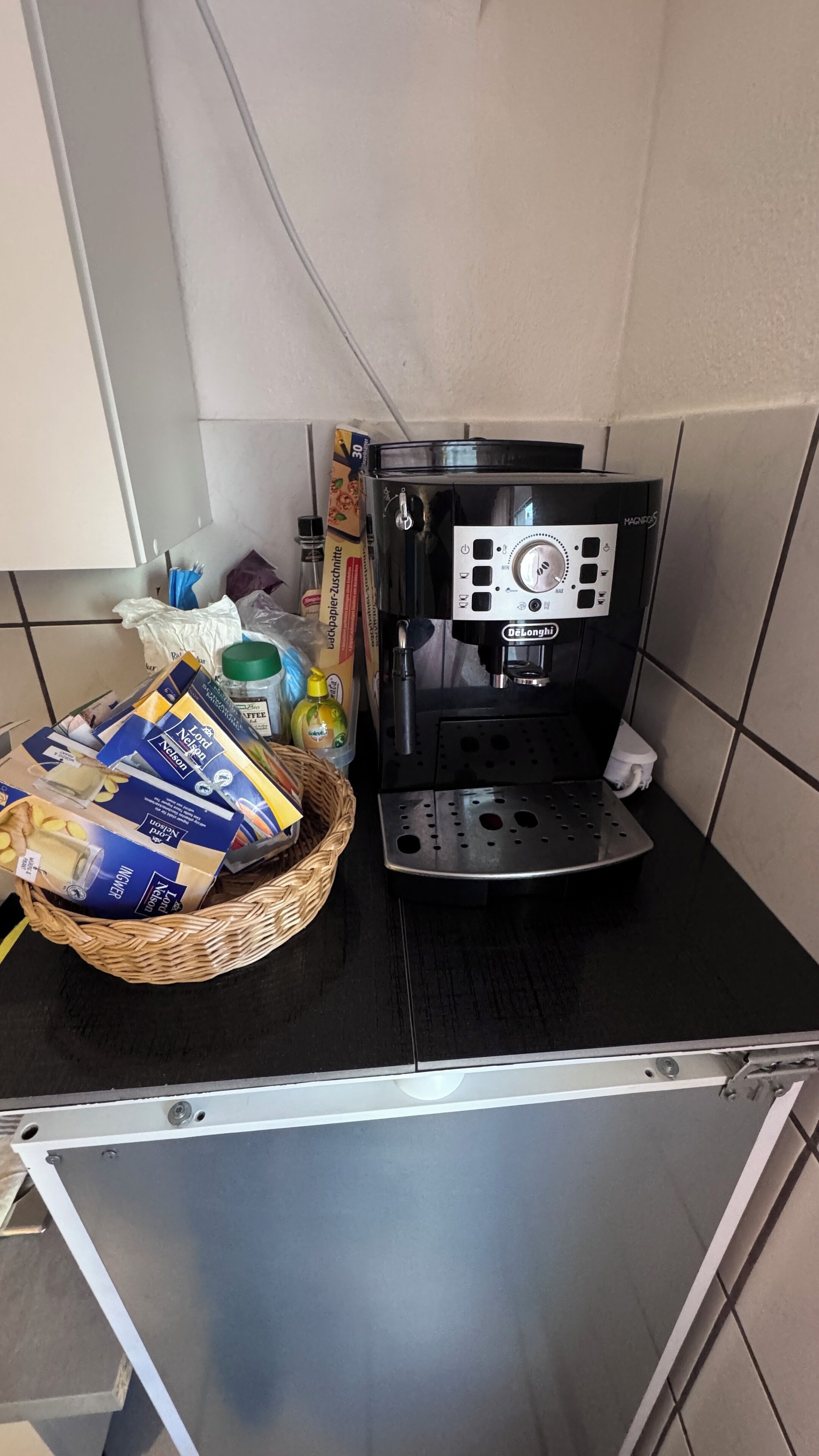 Una cocina con cafetera, una cesta de pan y algunos alimentos envasados.