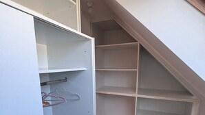 Een kamer met een witte kledingkast, een houten vloer en een inbouwkast.