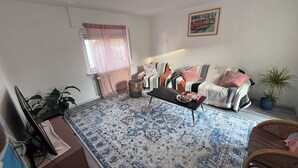 Een woonkamer met een bank, een salontafel, een televisie en een potplant.