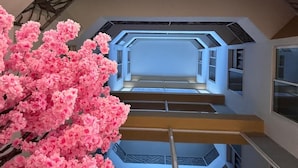 A multi-level interior with a central staircase, geometric wall patterns, and a large artificial pink flower arrangement. - Hotel Rosales Suites (Pereira)