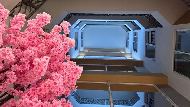 A multi-level interior with a central staircase, geometric wall patterns, and a large artificial pink flower arrangement. - Hotel Rosales Suites (Pereira)