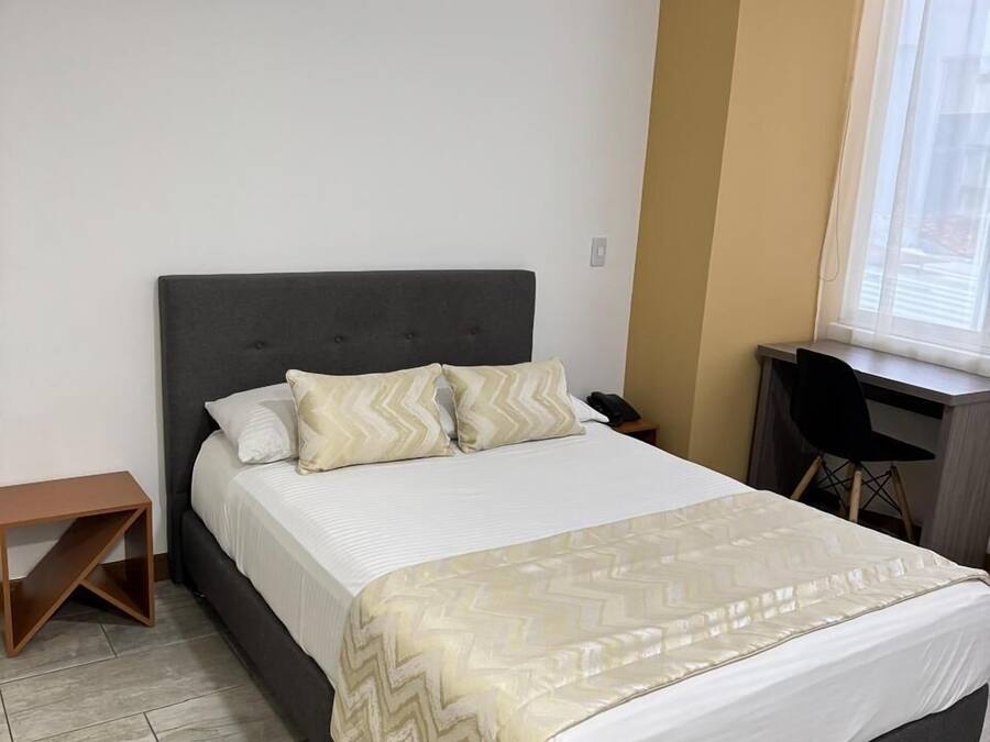 A neatly arranged bedroom with a bed, a desk, and a chair.