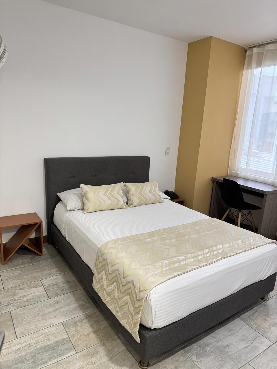 A neatly arranged bedroom with a bed, a desk, and a chair.
