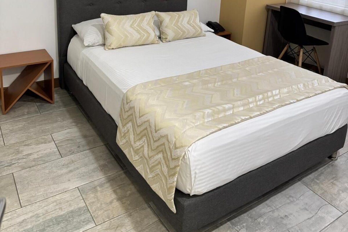 A neatly arranged bedroom with a bed, a desk, and a chair.