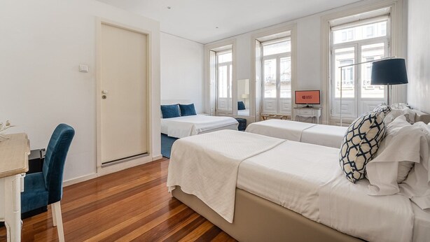 A hotel room with two beds, a desk, a chair, and a TV. - GuestReady - House Marquês - Ponte S. João (Porto)