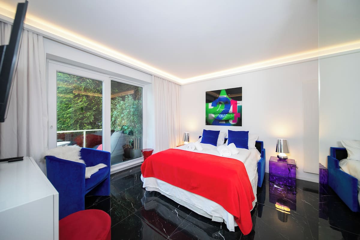 Quarto de hotel moderno com cama grande, escrivaninha e televisão.