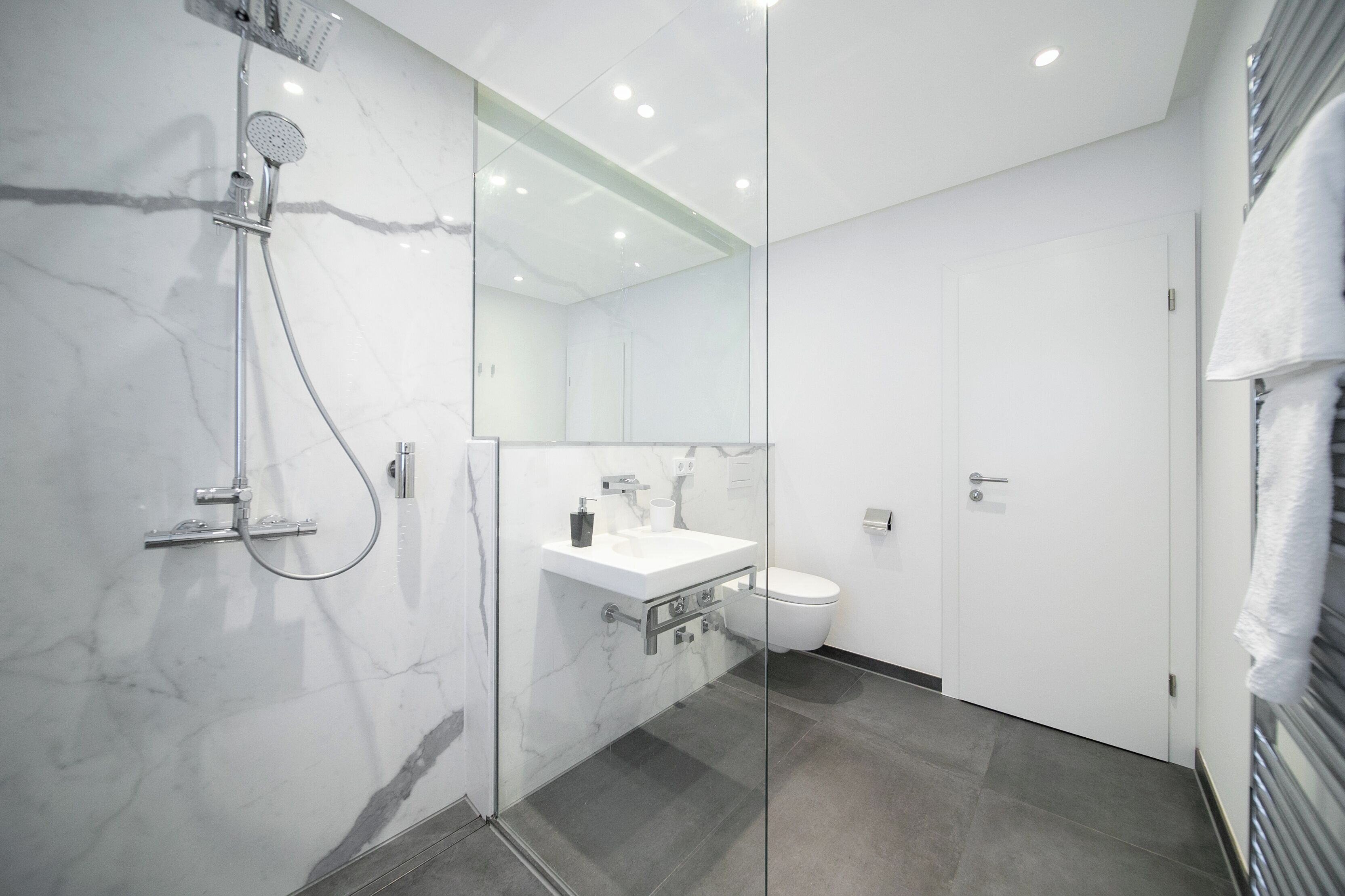 A modern bathroom with a glass-enclosed shower, a white sink, and a toilet.