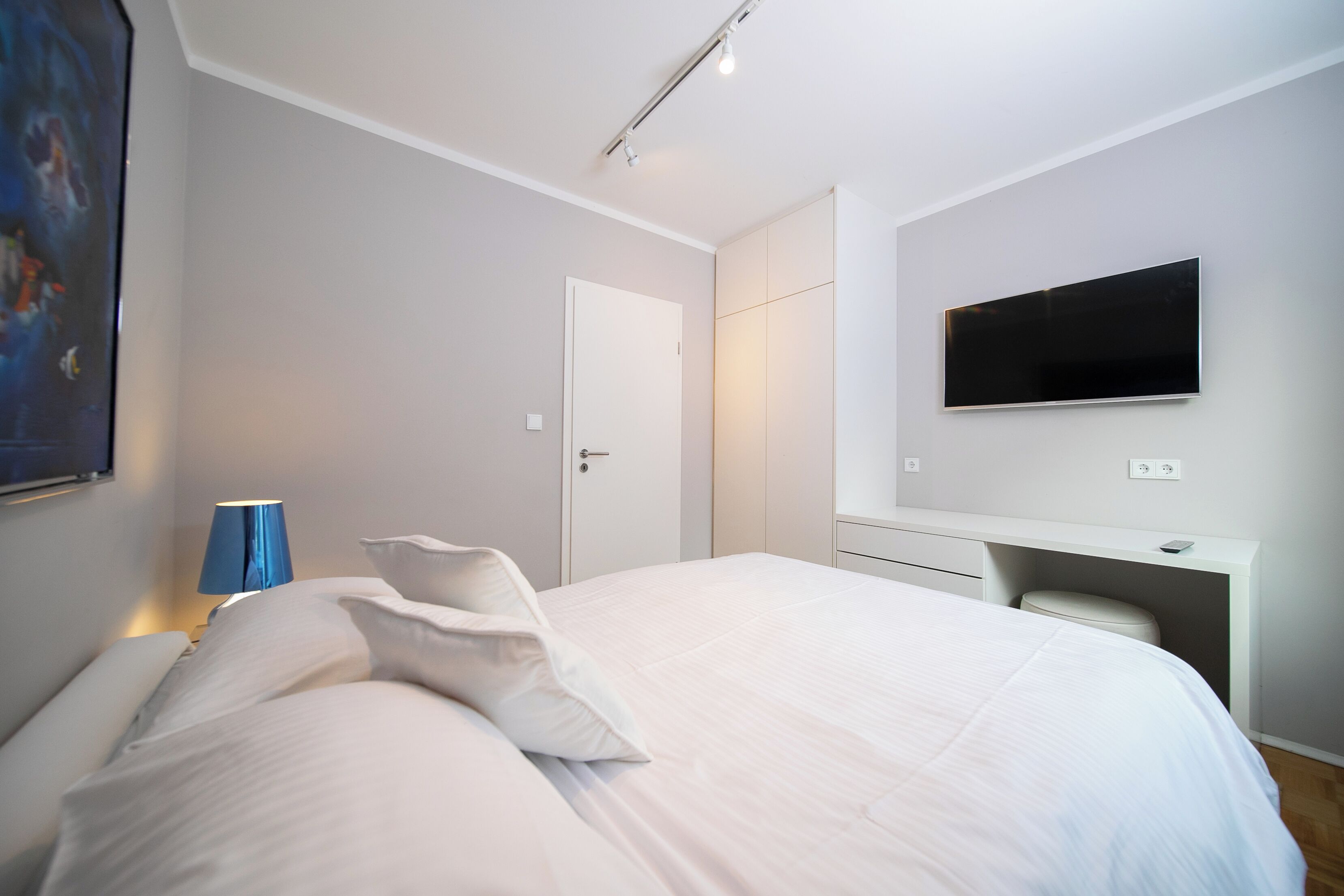 Un dormitorio moderno con cama, escritorio y televisor.