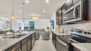 Una cocina moderna con una isla grande, electrodomésticos de acero inoxidable e iluminación colgante.