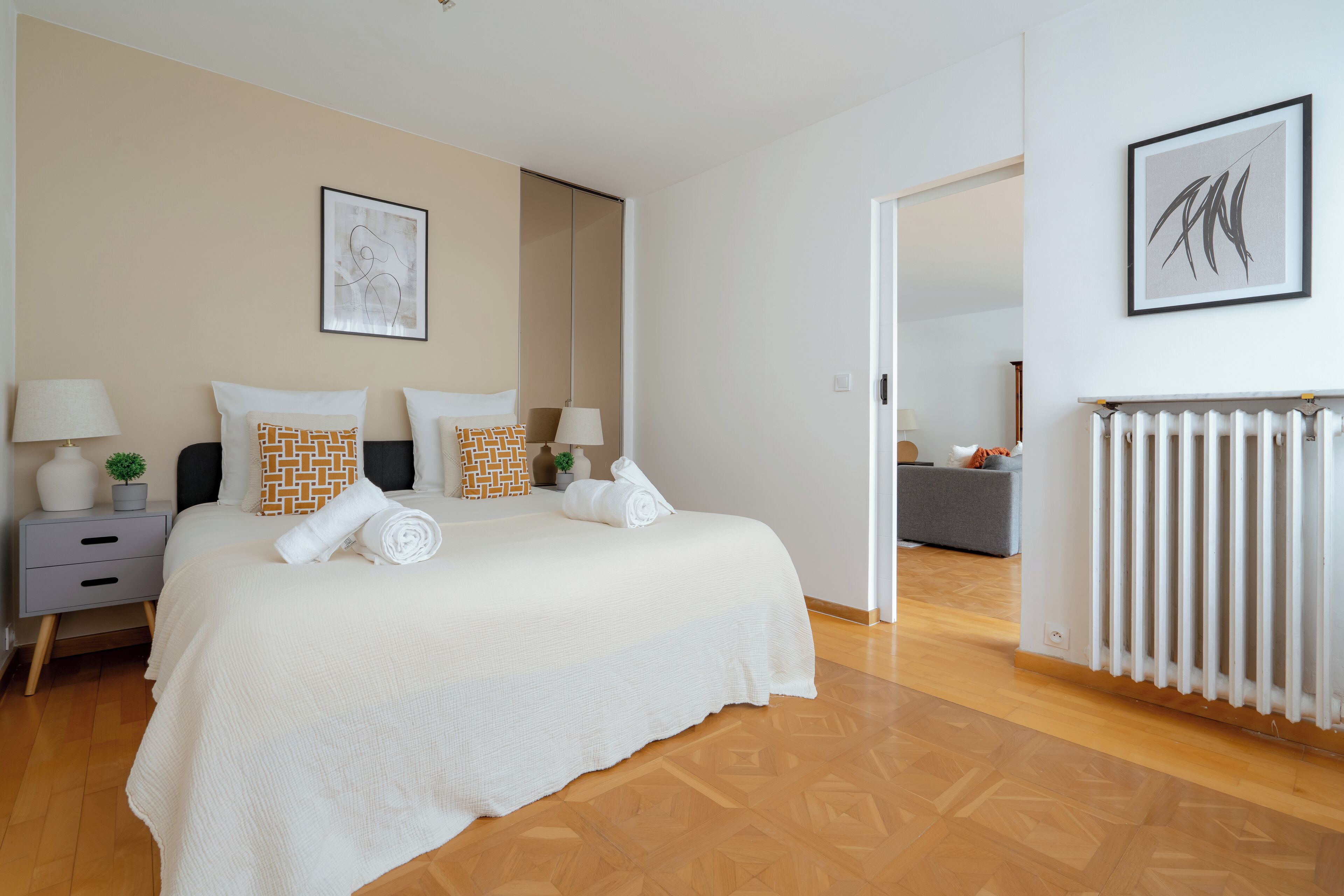 Un dormitorio con una cama grande, dos mesitas de noche, un radiador y un espejo.