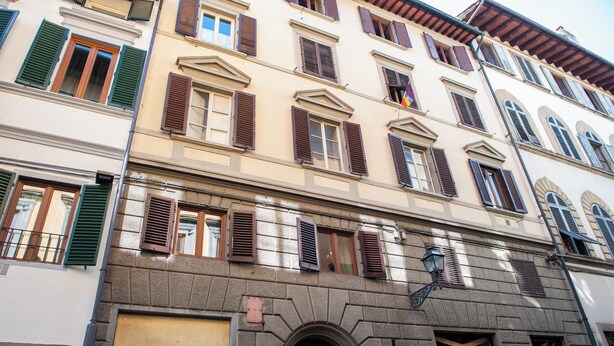 A multi-story building with a ground-level entrance, a visible shop on the left, and a staircase leading to the upper floors. - Oriuolo - Flo Apartments (Firenze)