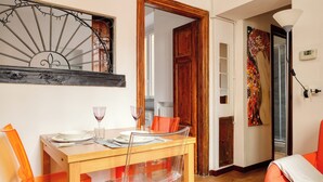 A dining area with a wooden table, clear chairs, and a decorative mirror. - JOIVY Welcoming flat in Porta Garibaldi (Milan)