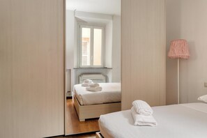 A modern hotel room with a large bed, a bedside table, a lamp, and a window with blinds. - JOIVY Welcoming flat in Porta Garibaldi (Milan)