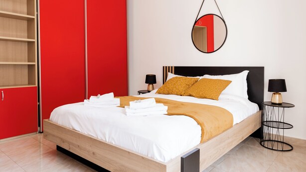 A modern bedroom with a wooden bed, red wardrobe, and a round mirror on the wall. - Maffi's House - Two Bedroom Apartment, Sleeps 4 (Rome)
