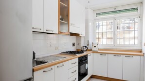 A modern kitchen with white cabinets, a stove, and a window with blinds. - Maffi's House - Two Bedroom Apartment, Sleeps 4 (Rome)