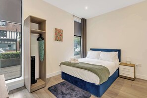 Quarto moderno com cama, mesa de cabeceira e guarda-roupa.