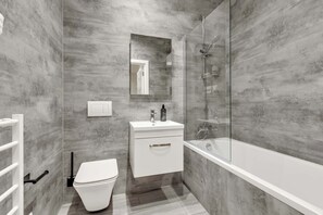 Uma casa de banho moderna com cabine de duche em vidro, lavatório branco e sanita.