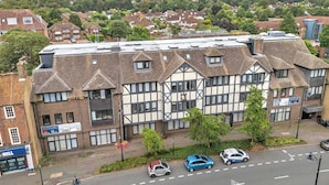 A multi-story building with a mix of residential and commercial spaces, featuring a prominent clock tower and a visible storefront on the ground floor.