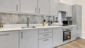 A modern kitchen with grey cabinets, a stainless steel oven, and a microwave.