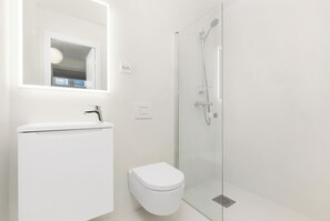 Ein modernes Badezimmer mit einem weißen Waschbecken, einer Toilette und einer begehbaren Glasdusche.