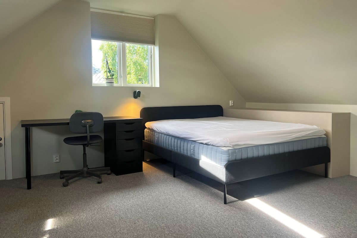 Un dormitorio con cama, escritorio, silla y ventana con persianas.