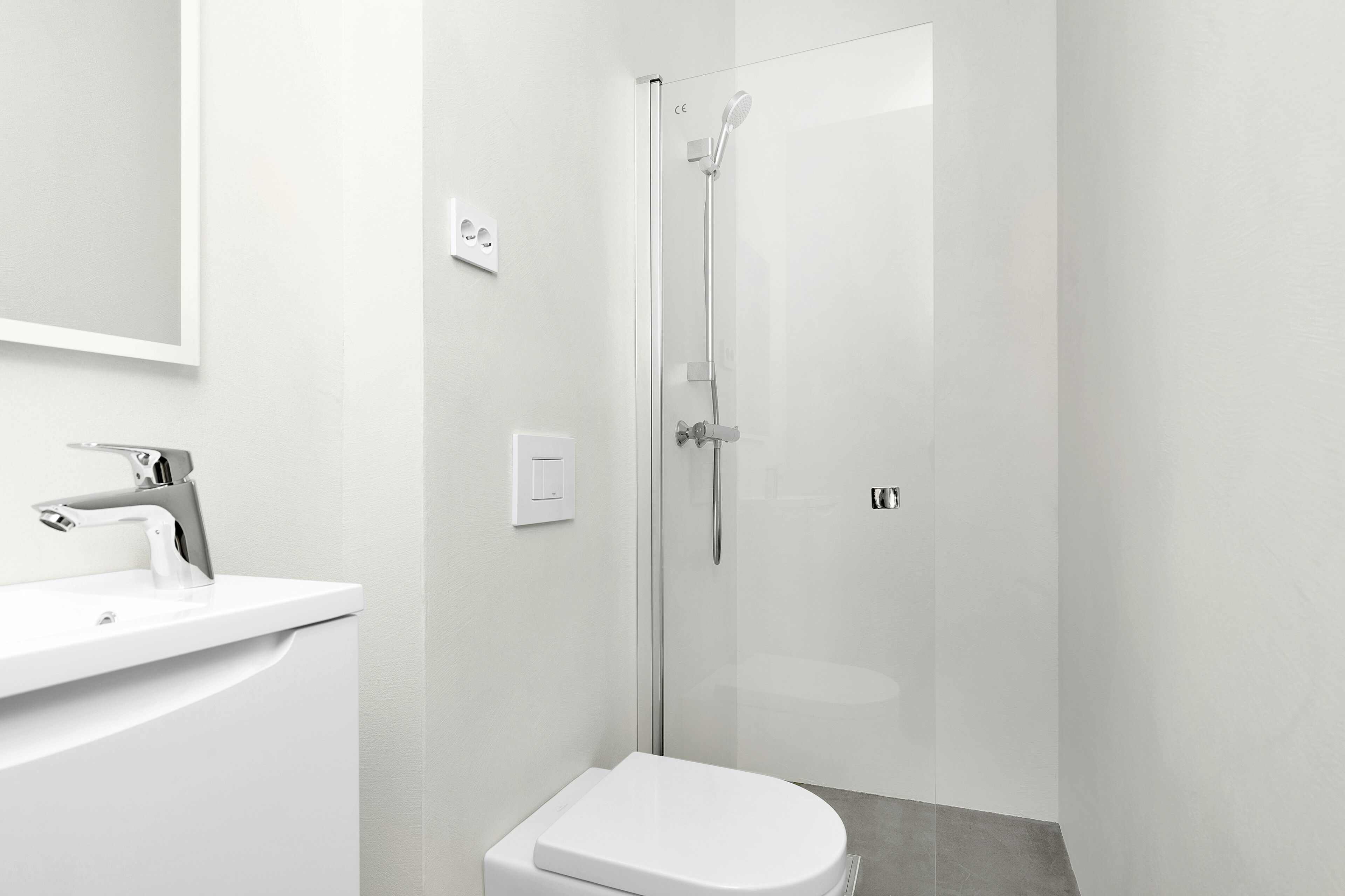 A modern bathroom with a white sink, toilet, and glass-enclosed shower.