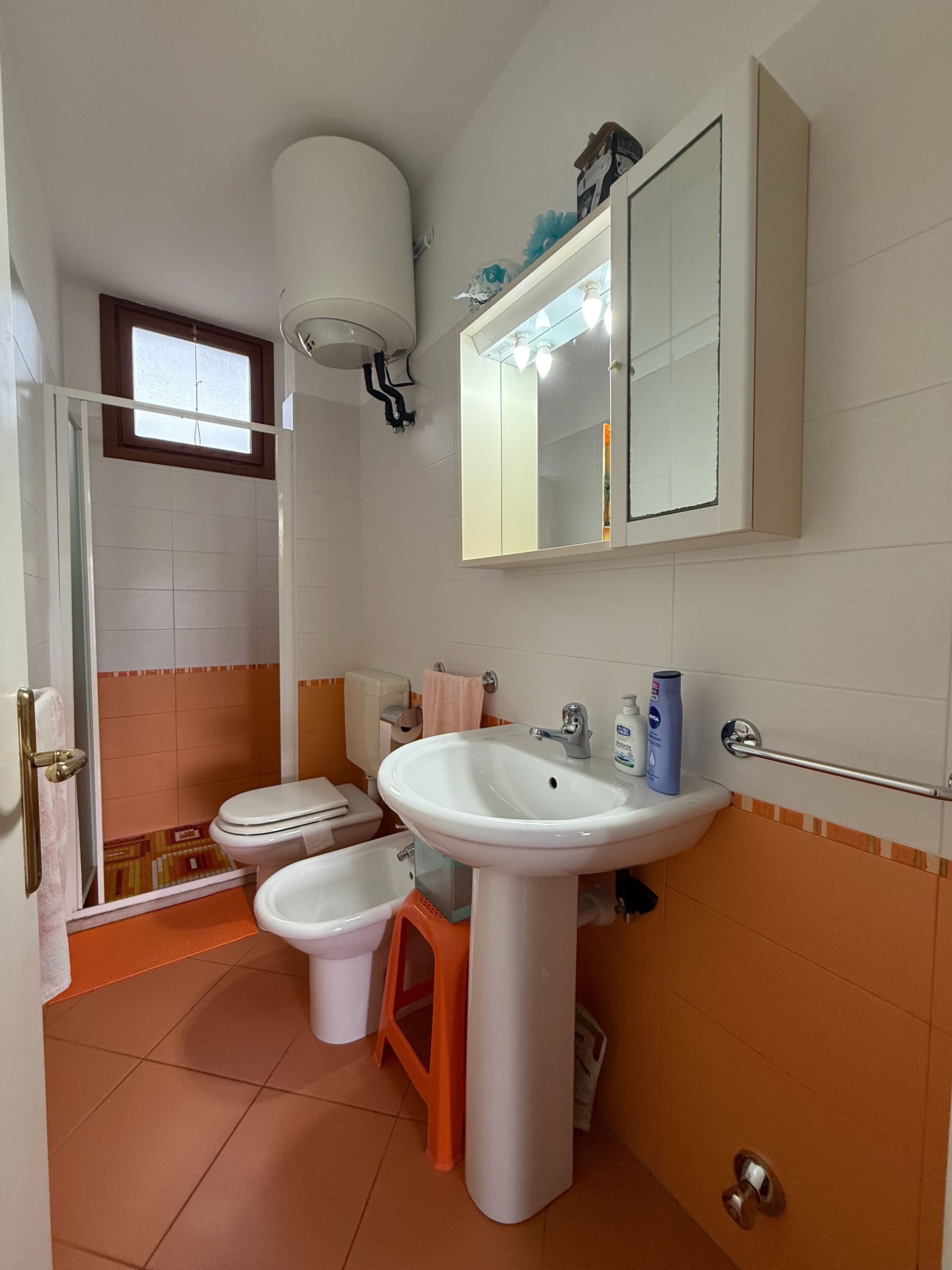 Ein Badezimmer mit Toilette, Bidet, Waschbecken und einem Fenster.
