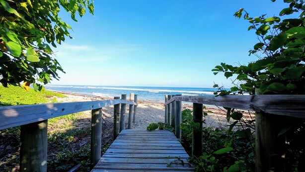 Un muelle de madera que lleva a una playa con vistas al océano.