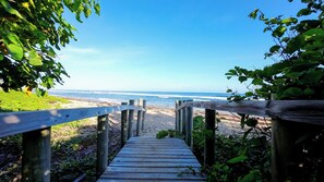 Une promenade en bois menant à une plage avec vue sur l’océan.