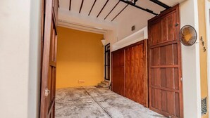A narrow entrance with a concrete floor leading to a yellow wall and a wooden door. - CASA LA ESCONDIDA (Mérida)