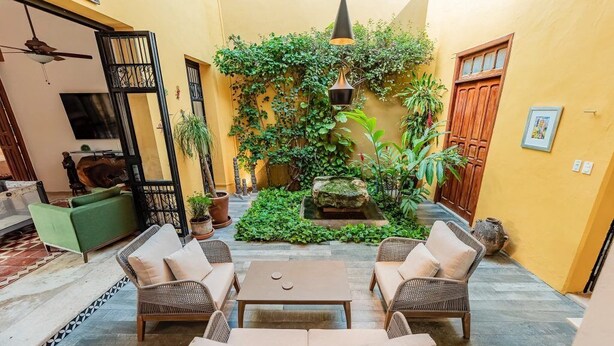 A courtyard with wicker furniture, a stone table, and a small rock garden. - CASA LA ESCONDIDA (Mérida)