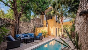 A pool area with a sofa set and a stone wall. - CASA LA ESCONDIDA (Mérida)