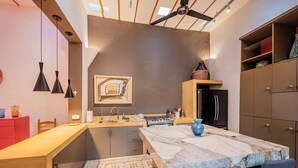 A modern kitchen with a marble countertop, a built-in oven, and a black refrigerator. - CASA LA ESCONDIDA (Mérida)