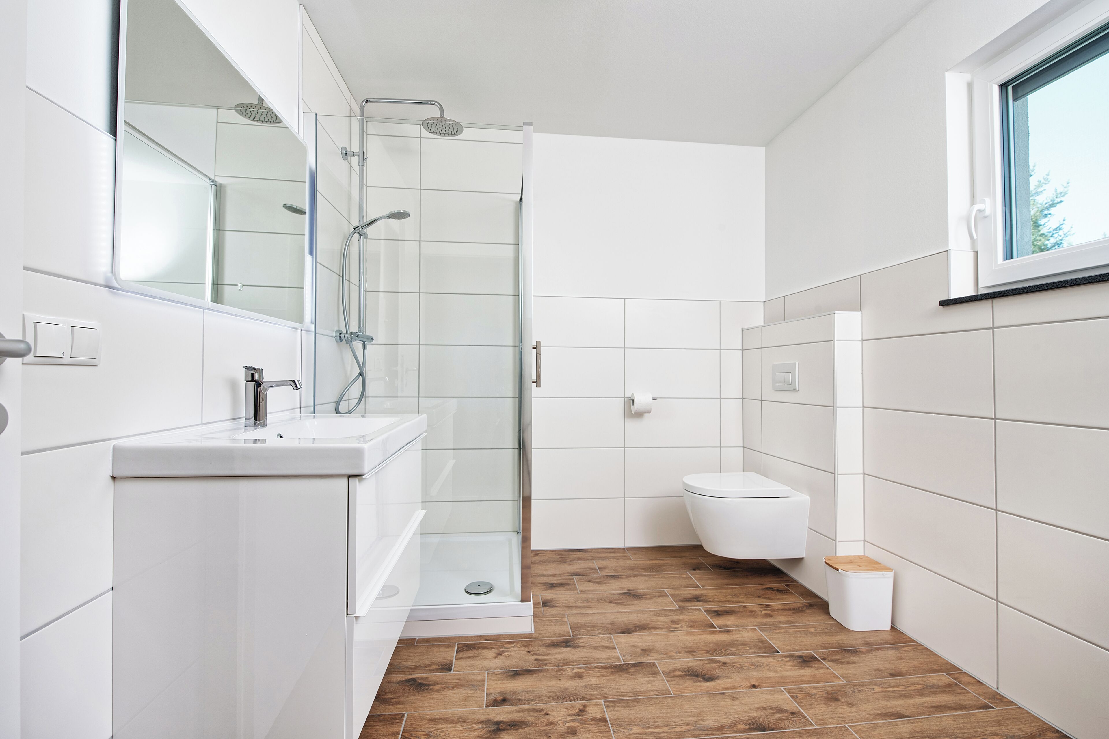 Ein modernes Badezimmer mit Duschkabine aus Glas, einem weißen Waschbecken und einer Toilette.
