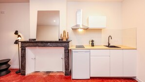 A modern kitchen with white cabinets, a black countertop, a built-in dishwasher, and a stainless steel range hood. - Le Balcon de Lavaur – Views & Charm in the Heart of the City (Lavaur)