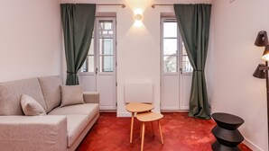 A room with a sofa, a small table, a lamp, and a radiator. - Le Balcon de Lavaur – Views & Charm in the Heart of the City (Lavaur)