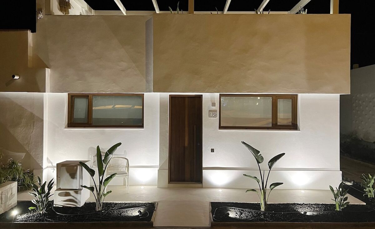 Un edificio moderno con tetto piatto, ingresso centrale e due finestre al piano terra.