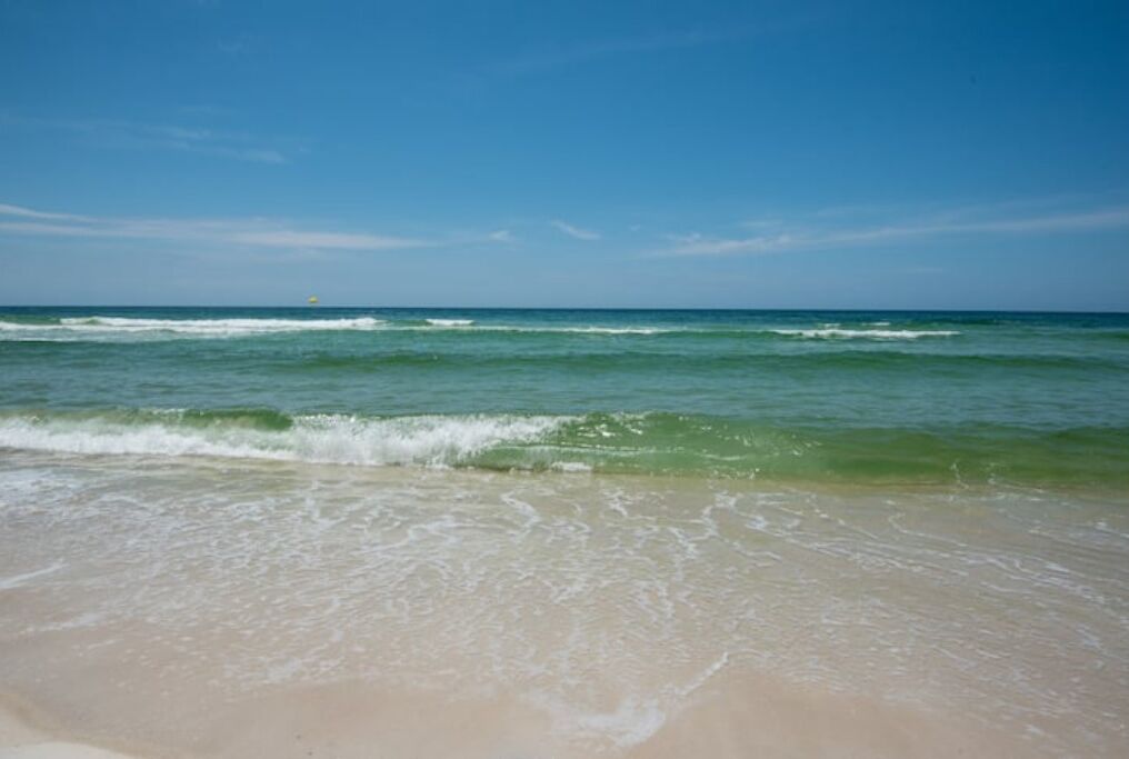 Een strand met helderblauw water en een zandstrand.
