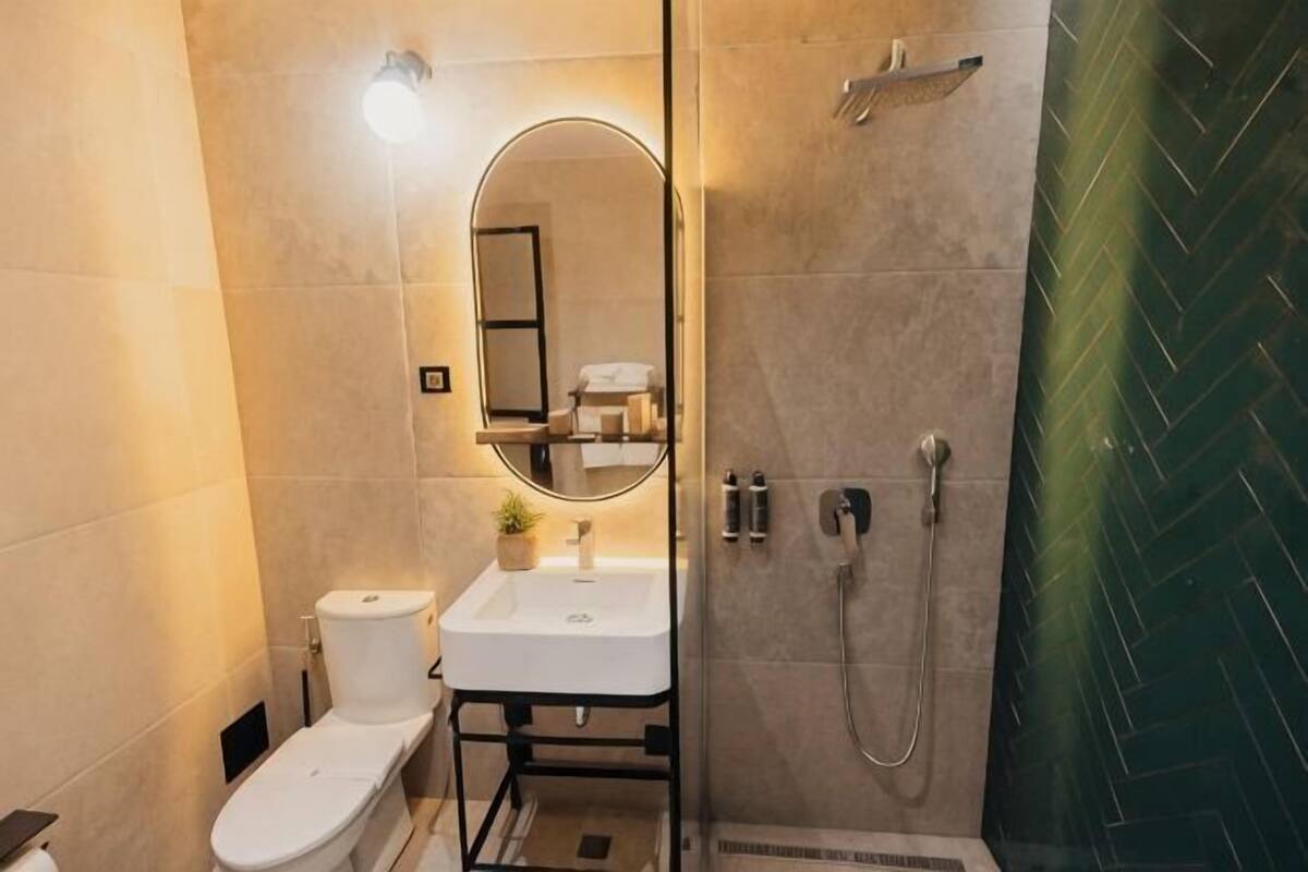 A bathroom with a toilet, sink, mirror, and shower.