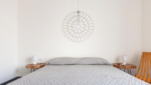 Ein Schlafzimmer mit einem Bett, zwei Nachttischen, einem Holzstuhl und einer Wanddekoration.