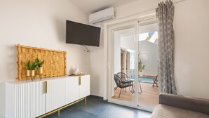 Ein modernes Wohnzimmer mit einer weißen Kommode, einem Flachbildfernseher und einer Glastür, die zu einer Außenpatio führt.