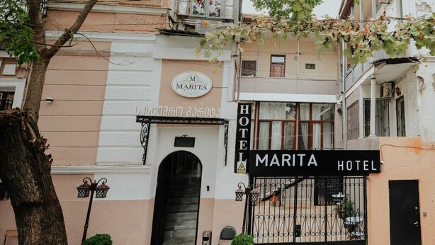 L'esterno dell'Hotel Marita, con un cancello nero, piante in vaso e un cartello che indica il nome dell'hotel.