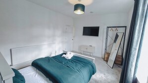 A modern bedroom with a bed, a white dresser, a mirror, and a TV on the wall. - Bristol City Center - Cosy 2 Bedroom House (Bristol)
