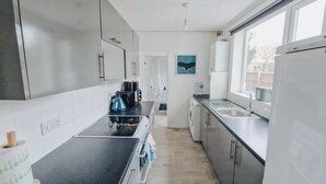 A modern kitchen with a black countertop, stainless steel appliances, and a view of the outside through a window. - Bristol City Center - Cosy 2 Bedroom House (Bristol)