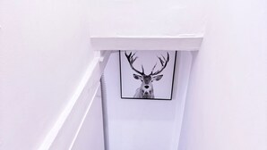 A staircase with carpeted steps leading to a landing with a framed deer head artwork. - Bristol City Center - Cosy 2 Bedroom House (Bristol)