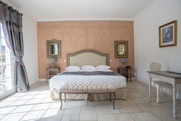 A bedroom with a large bed, two bedside tables, a chair, and a window with curtains.