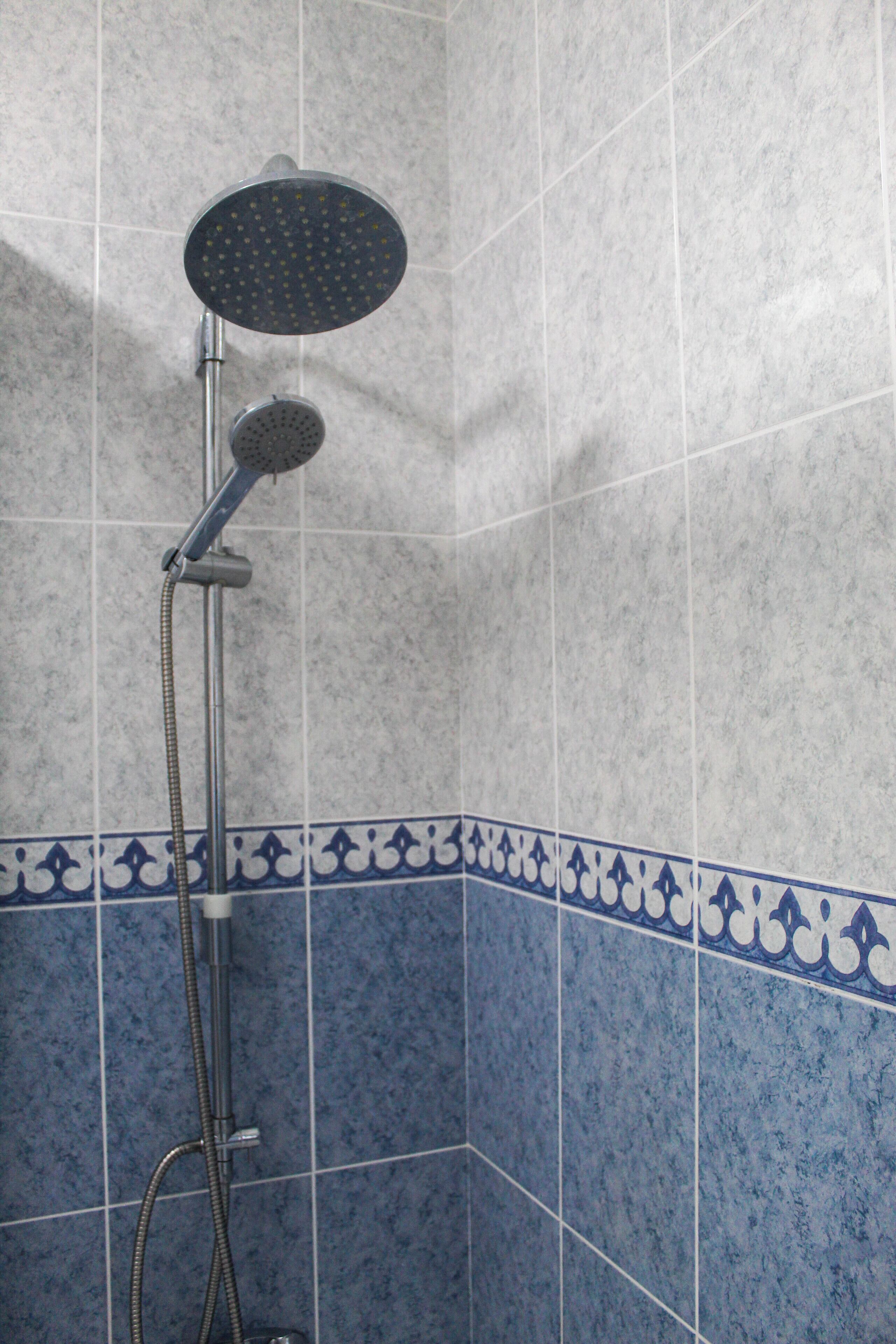 A shower with a handheld showerhead and a wall-mounted faucet.